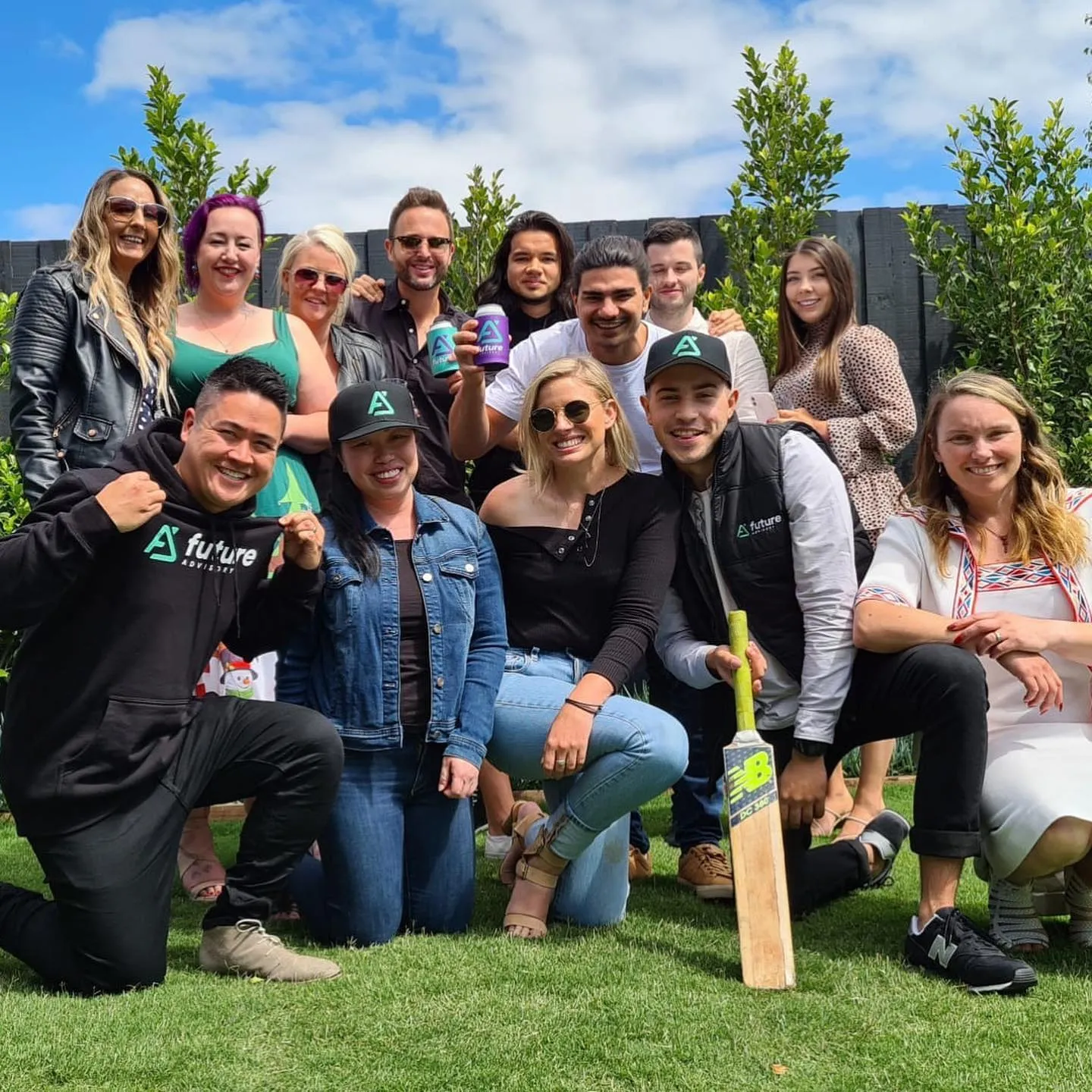 The Future Advisory team posing on a lawn with drinks and a cricket bat