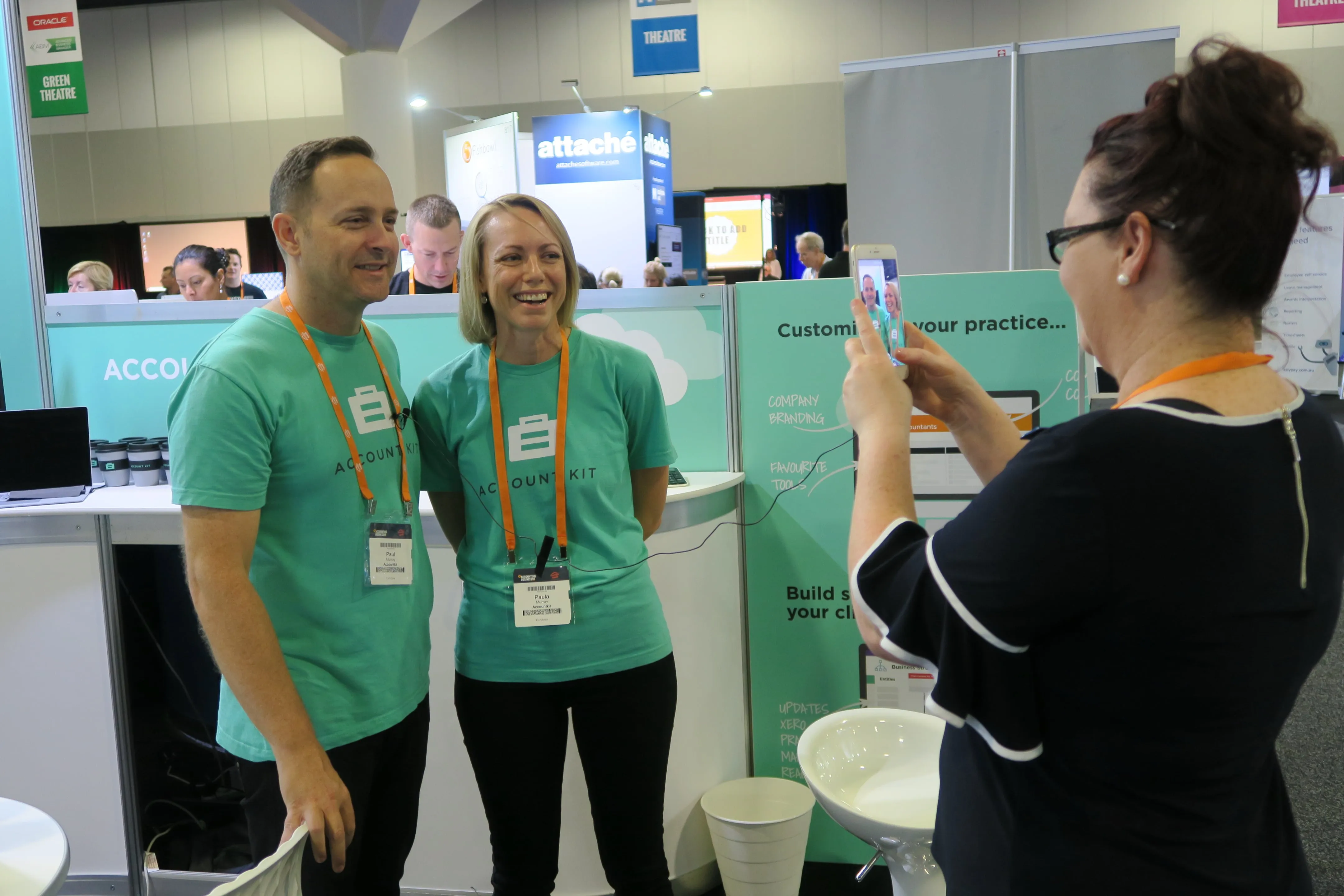 A visitor photographs two AccountKit team members at the AccountKit expo stand
