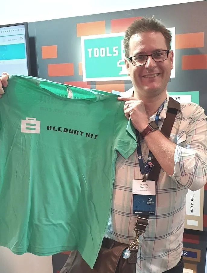 Jeremy Wotton holding up an AccountKit T-shirt at a conference stand