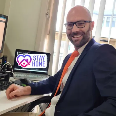Matt Gaffney of AccountKit working from his desk, with a Stay Home sticker over his laptop screen
