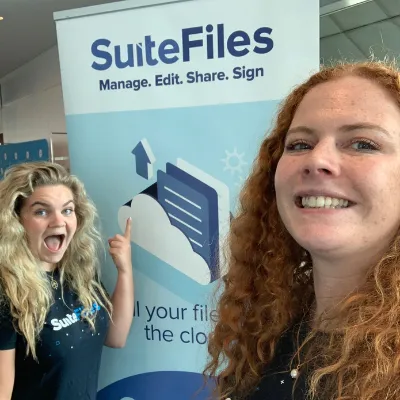 Molly Banister and a SuiteFiles colleague taking a selfie in front of a SuiteFiles banner